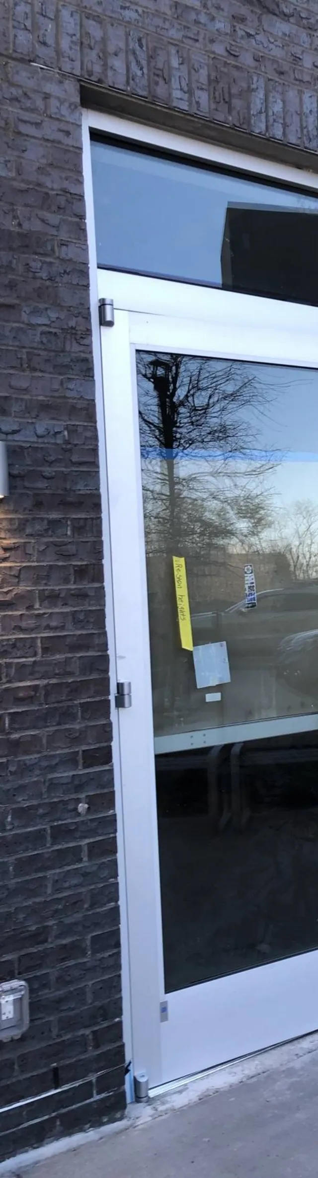 Puerta de storefront de aluminio y vidrio recién instalada en una fachada de ladrillo