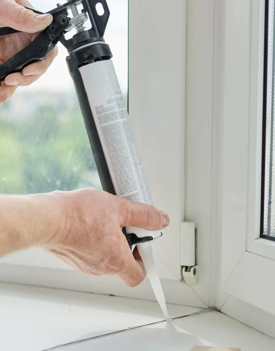 Pistola de caulking aplicando sellador en la junta de una ventana